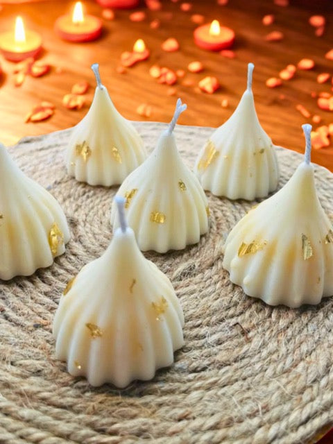 Decorative candles with gold accents on a textured surface with blurred candles in the background.
