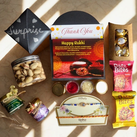 Gifting items including a card, snacks, and candles on a textured surface.