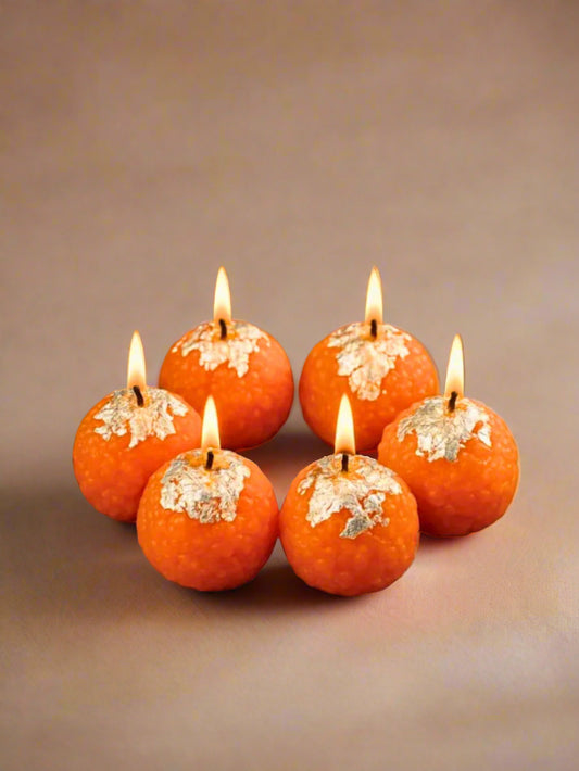 Orange candles with silver foil against a clear background