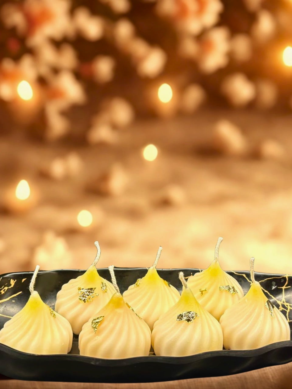 Decorative candles on a black tray with a warm, blurred background